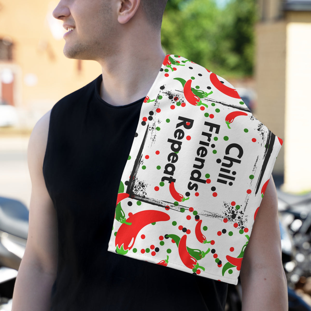 Man holding Chili Friends Repeat kitchen towel with colorful chili pepper design