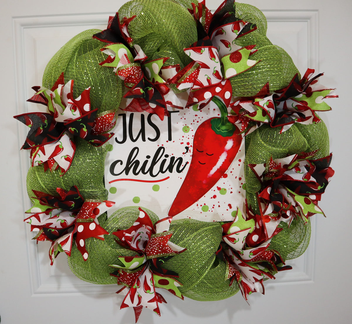 Handmade chili pepper wreath displayed on white front door