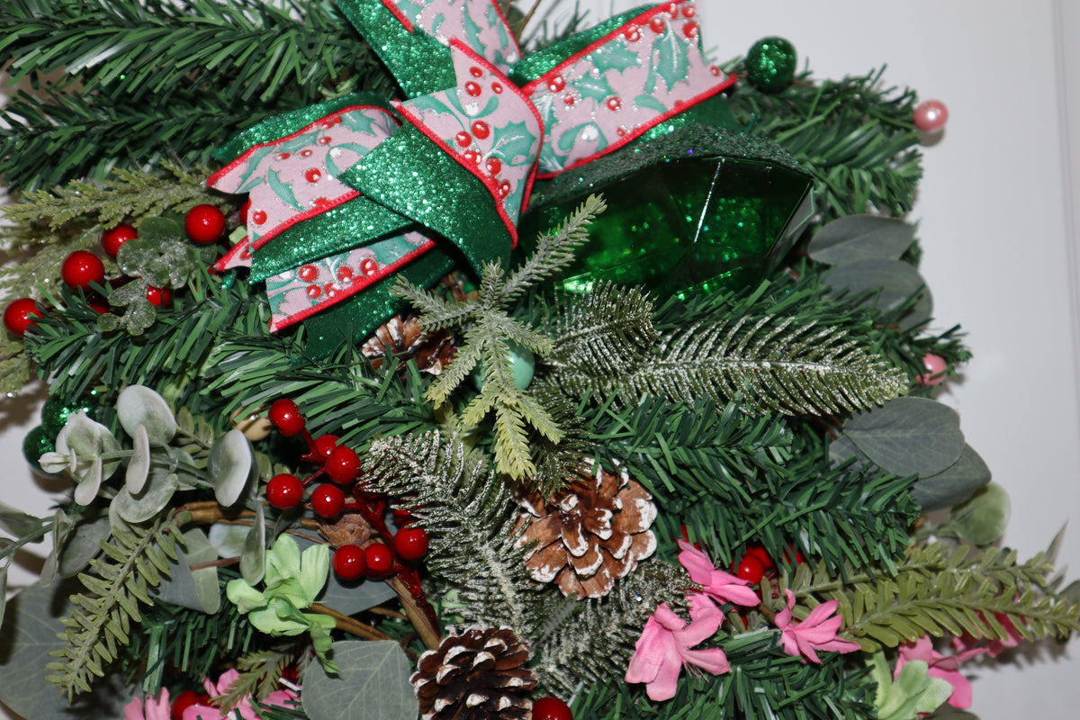 Close-up of holly ribbon and emerald green gem on Christmas swag