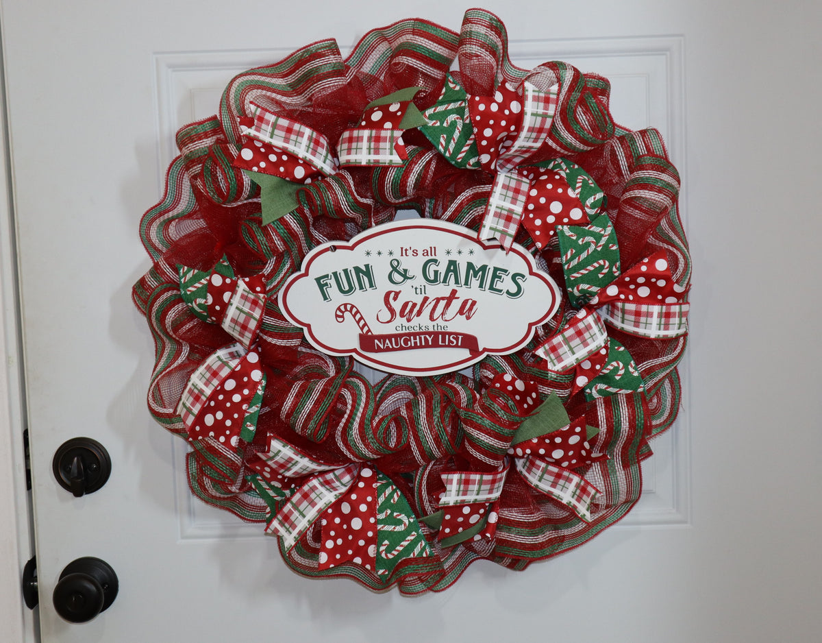 Red and green Christmas mesh wreath displayed on a white front door