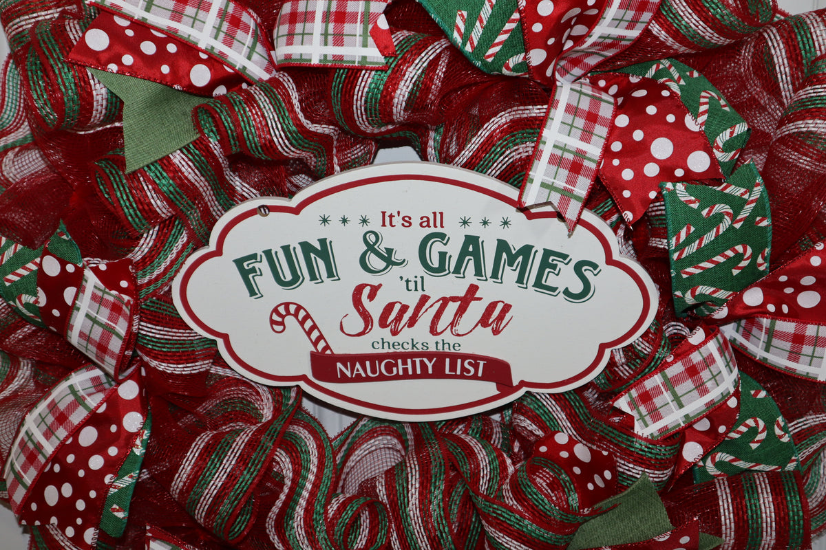 Close-up of decorative Christmas sign on red and green mesh wreath