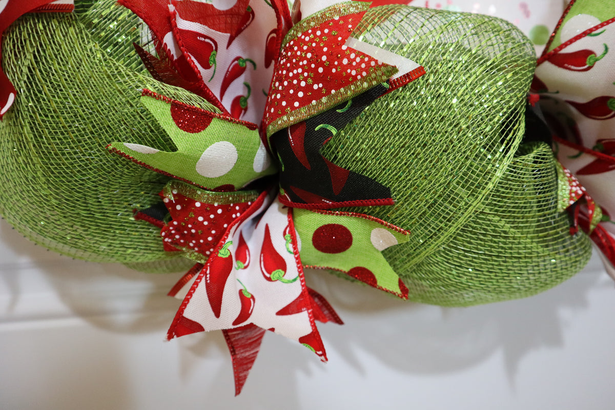 Close-up view of chili pepper ribbon and green mesh wreath