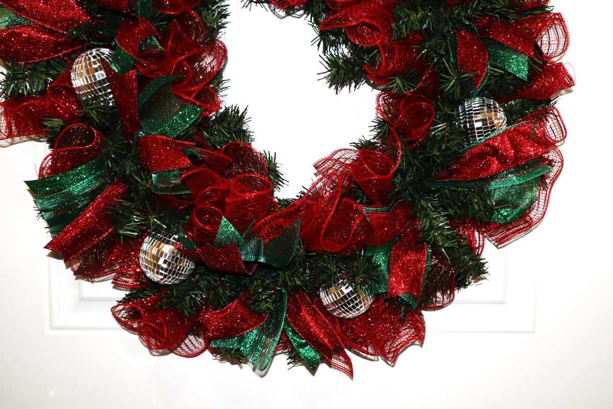 Lower detail of Christmas wreath with red mesh green ribbon and mirrored ornaments