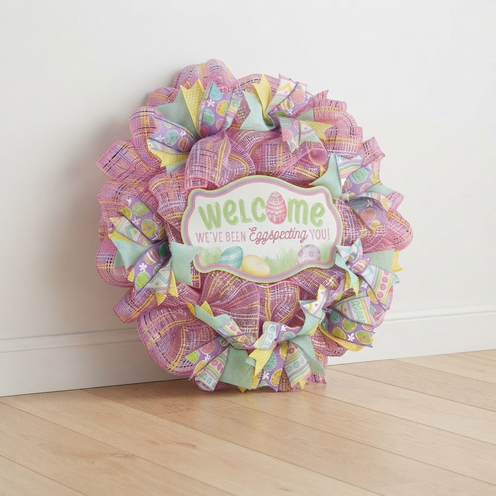 Welcome Easter mesh wreath with pink mesh and pastel ribbons standing against a white wall