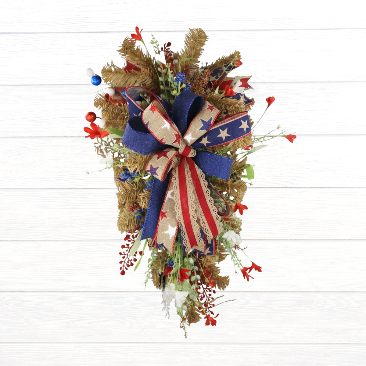 Handmade patriotic front door swag against a white shiplap wall