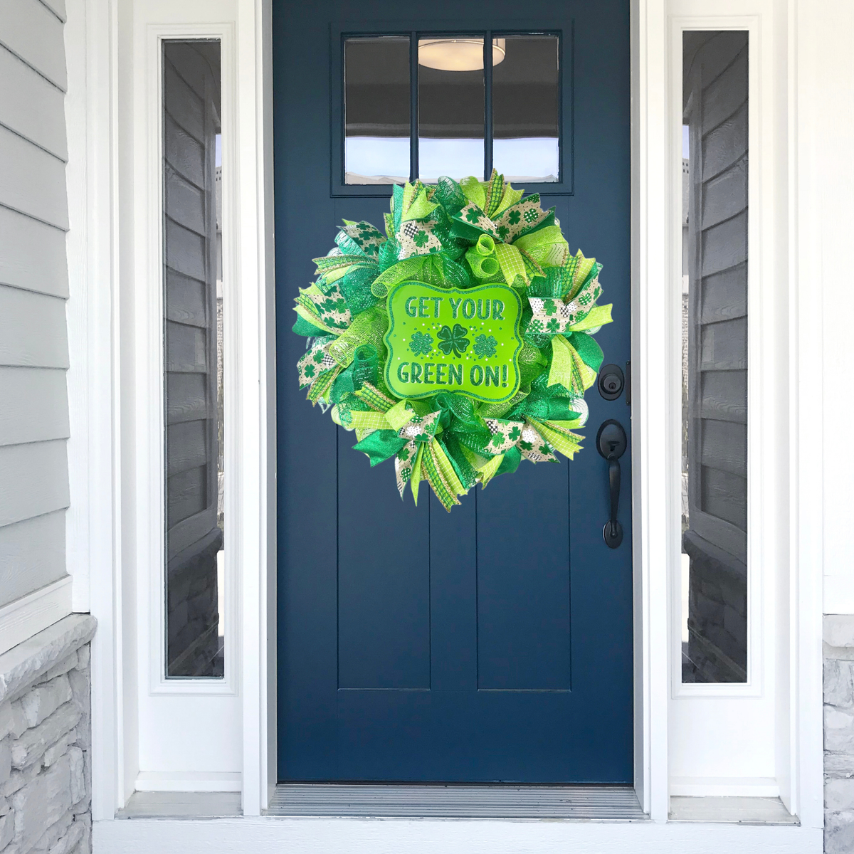 Handmade St. Patrick's Day wreath displayed on a navy blue front door