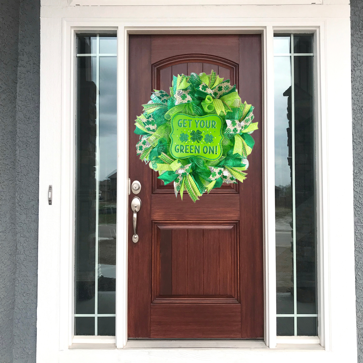 Green mesh shamrock wreath displayed on a dark wood front door