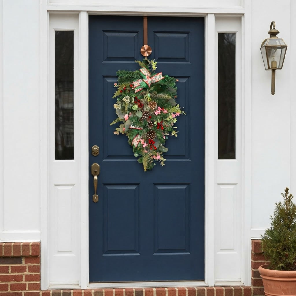 Emerald green and pink Christmas teardrop swag displayed on navy front door