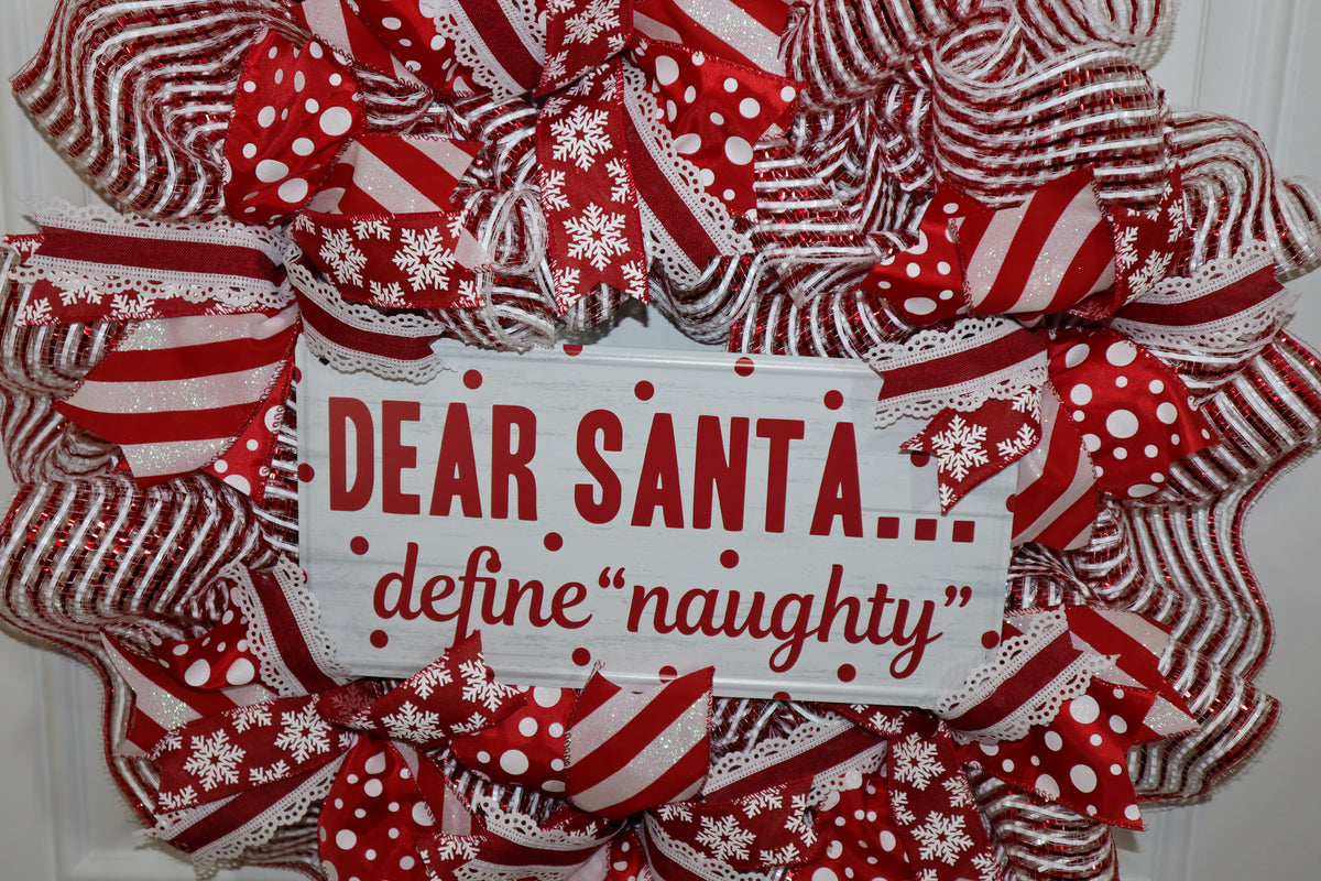 Close-up of decorative metal Christmas sign on red and white wreath